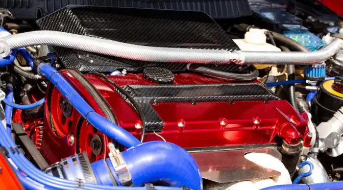 Zmodyfikowany silnik z czerwoną pokrywą zaworów, elementami z włókna węglowego (carbon) i niebieskimi przewodami silikonowymi.